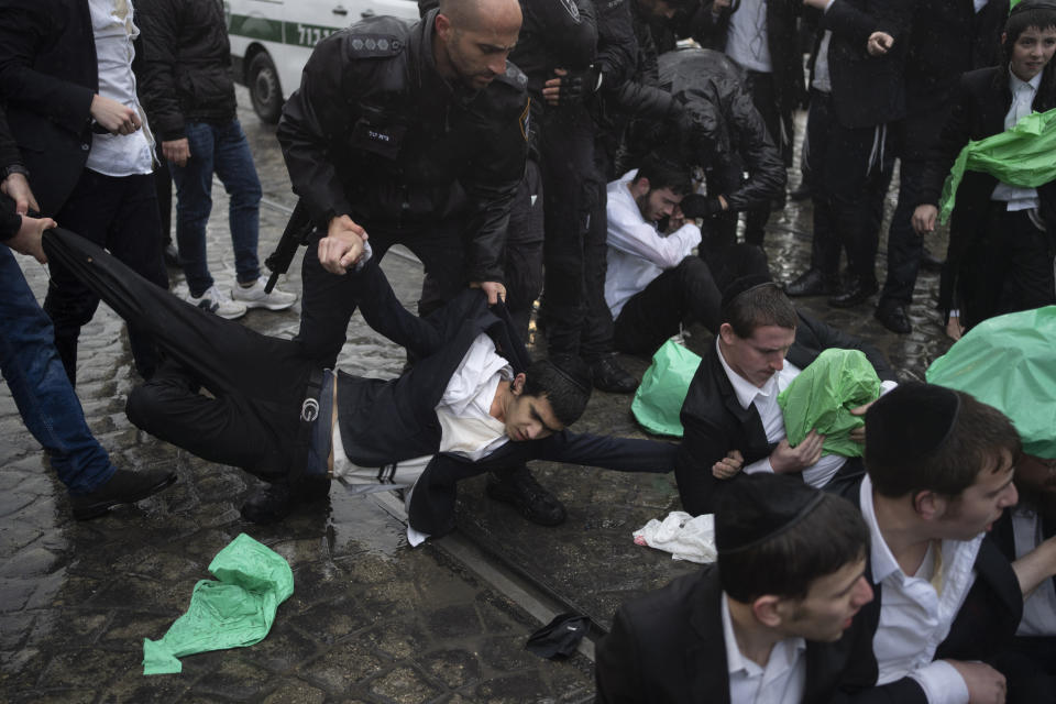 Israeli police officers scuffle with ultra-Orthodox Jewish men during a protest against a potential new draft law that could end their exemptions from military service in Jerusalem, Israel, Monday, March 18, 2024. (AP Photo/Leo Correa)