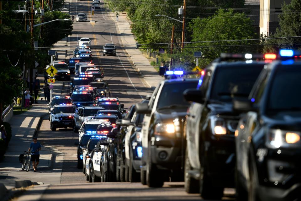 Dozens of police vehicles line up in a procession June 21 in the aftermath of a shooting in Arvada, Colo., in which a police officer was killed.