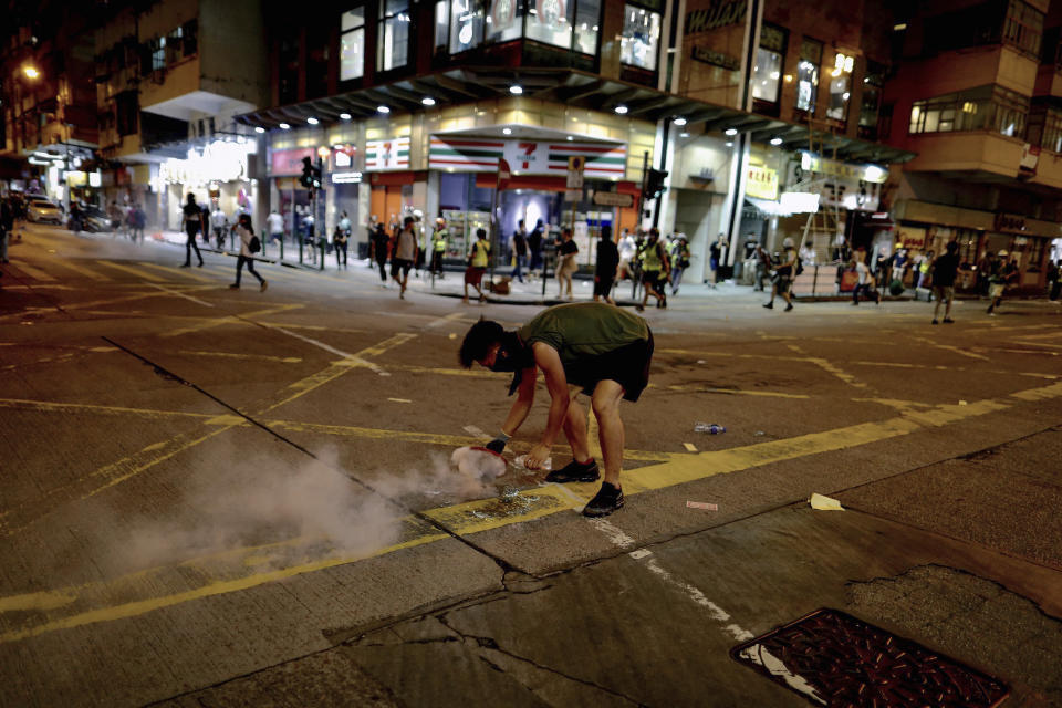 A protester uses a plate to cover a tear gas during clashes with policemen near the Shum Shui Po police station in Hong Kong on Wednesday, Aug. 14, 2019. German Chancellor Angela Merkel is calling for a peaceful solution to the unrest in Hong Kong amid fears China could use force to quell pro-democracy protests. (AP Photo/Vincent Yu)