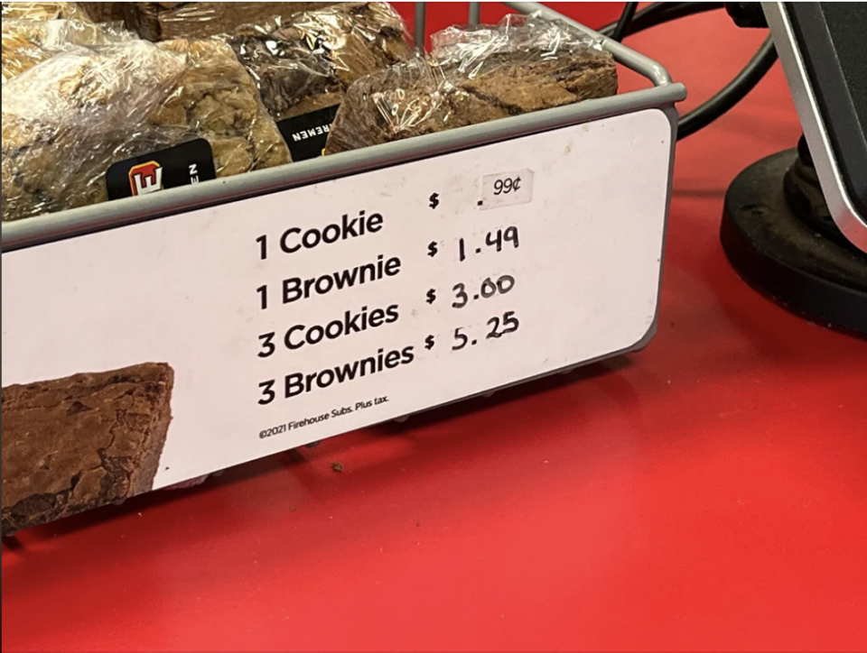 Menu displaying prices for cookies and brownies: 1 cookie 99 cents, 1 brownie $1.49, 3 cookies $3.00, 3 brownies $5.25