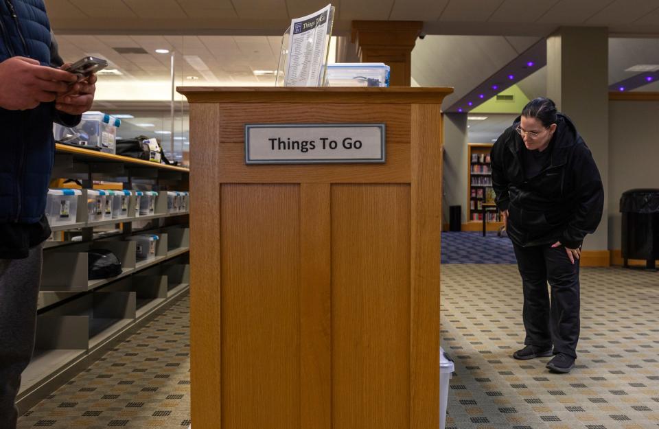 Rachel Al-Zubaidi looks through the Things to Go section inside the Clinton-Macomb Public Library in Clinton Township on Tuesday, Feb. 13, 2024. The Things to Go section, which consists of around 400 items, is divided into four categories: hobbies to go, tech to go, tools to go, and STEM to go kits.