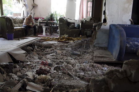 A local resident sits amidst debris at his damaged house, which according to locals was hit by recent shelling, in Donetsk, Ukraine, June 22, 2015. REUTERS/Alexander Ermochenko