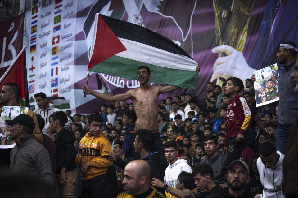 FILE - Palestinians wave their national flag as they watch a live broadcast of the World Cup quarterfinal soccer match between Morocco and Portugal played in Qatar, in Gaza City Saturday, Dec. 10, 2022. (AP Photo/Fatima Shbair, File)