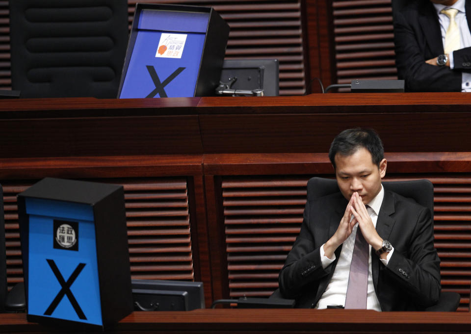 FILE - Pro-democracy lawmaker Dennis Kwok listens to a legislative debate next to a crossed-out sign to symbolize his opposition to the election reform proposals in Hong Kong, June 17, 2015. Hong Kong's leader said Tuesday, July 4, 2023, that eight pro-democracy activists who now live in the United States, Britain, Canada and Australia will be pursued for life for alleged national security offenses, dismissing criticism that the move to have them arrested was a dangerous precedent. (AP Photo/Vincent Yu, File)