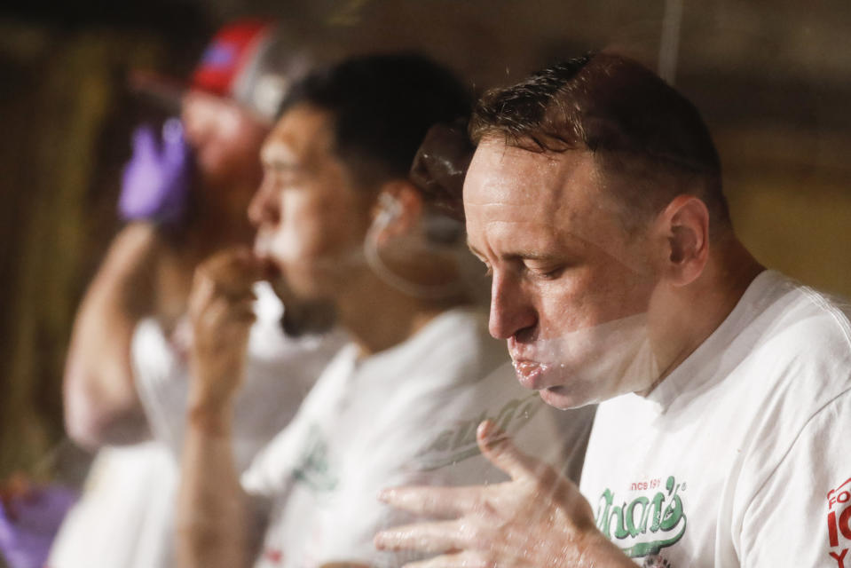 Competitive eater Joey Chestnut sets a new world record with 75 hot dogs to win the men's division of the Nathan's Famous July Fourth hot dog eating contest, Saturday, July 4, 2020, in the Brooklyn borough of New York. (AP Photo/John Minchillo)