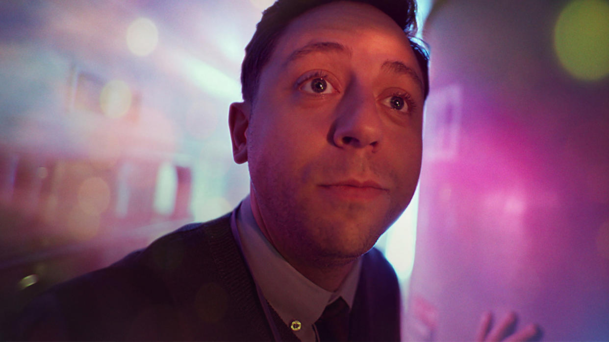  A man looks to the side of a camera with a colourful pink background. 