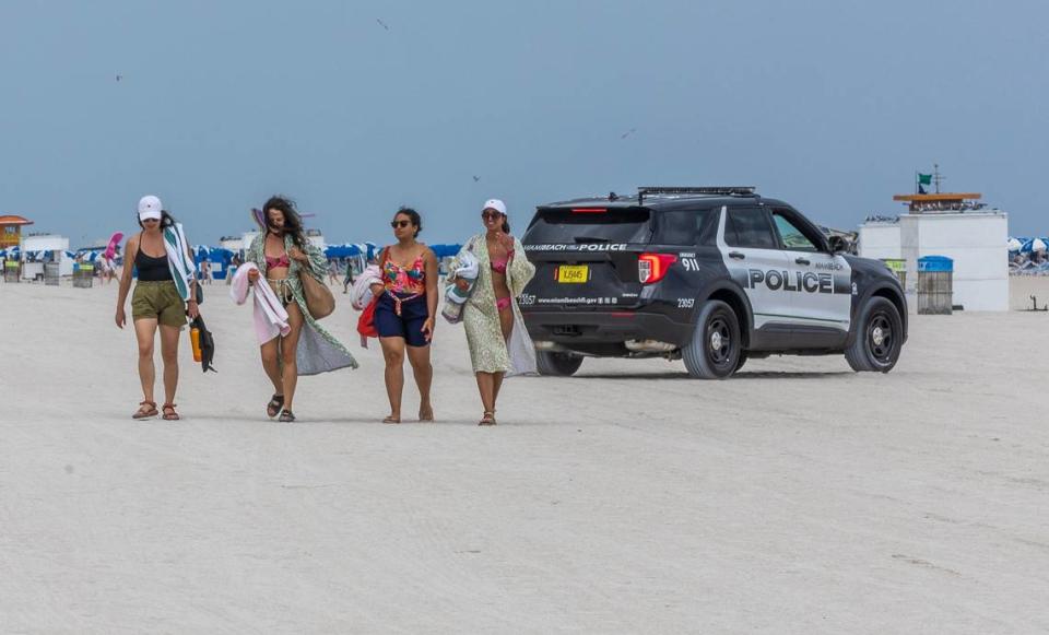 Una patrulla de la Policía de Miami Beach es vista junto a unas bañistas en la playa, durante las vacaciones de primavera en Miami Beach, el domingo 10 de marzo de 2024.