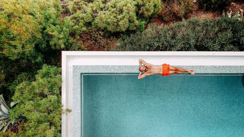 Aerial view of a young man relaxing by the infinity pool.