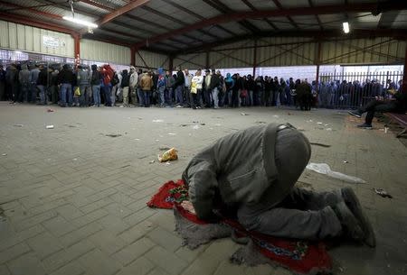 A man prays as Palestinians working in Israel wait to cross through Israeli Qalandiya checkpoint near the West Bank city of Ramallah April 25, 2017. REUTERS/Mohamad Torokman