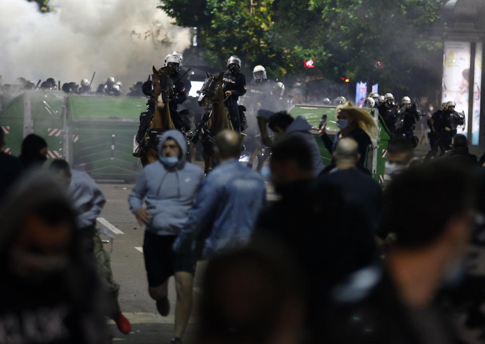 Sebian police officers disperse protesters in front of Serbian parliament building in Belgrade, Serbia, Wednesday, July 8, 2020. Thousands of people protested the Serbian president's announcement that a lockdown will be reintroduced after the Balkan country reported its highest single-day death toll from the coronavirus Tuesday. (AP Photo/Darko Vojinovic)