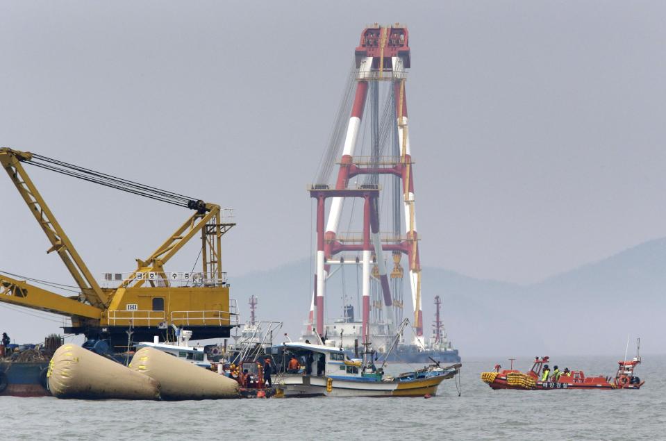 Searchers and divers look for people believed to have been trapped in the sunken ferry Sewol near the buoys which were installed to mark the vessel in the water off the southern coast near Jindo, south of Seoul, South Korea, Tuesday, April 22, 2014. One by one, coast guard officers carried the newly arrived bodies covered in white sheets from a boat to a tent on the dock of this island, the first step in identifying a sharply rising number of corpses from a South Korean ferry that sank nearly a week ago. (AP Photo/Lee Jin-man)