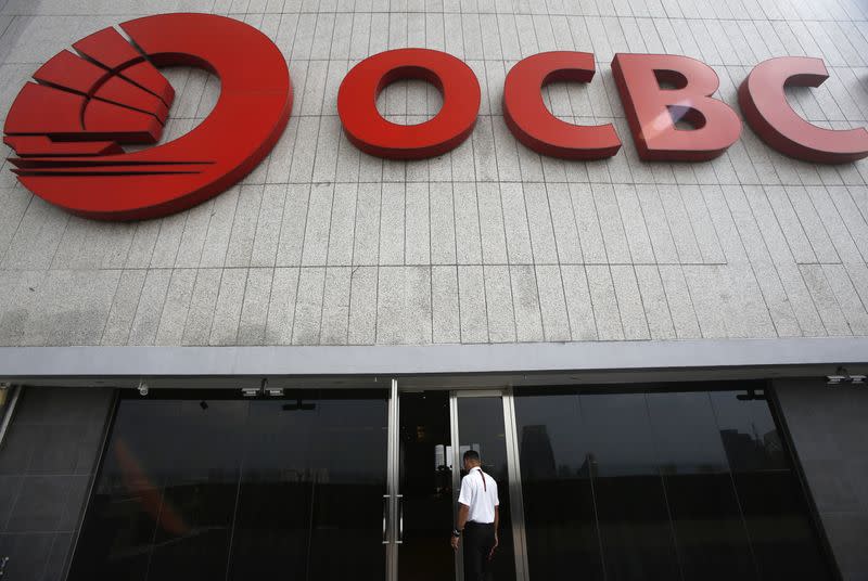 A security guard walks under a logo of Overseas-Chinese Banking Corp Ltd (OCBC) at the company's headquarters in Singapore