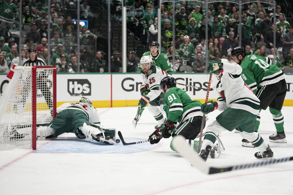 Dallas Stars center Tyler Seguin (91) reaches out to take a shot off a rebound, scoring against Minnesota Wild goaltender Filip Gustavsson (32), while Wild's Jonas Brodin (25) watches during the first period of Game 5 of an NHL hockey Stanley Cup first-round playoff series, Tuesday, April 25, 2023, in Dallas. (AP Photo/Tony Gutierrez)