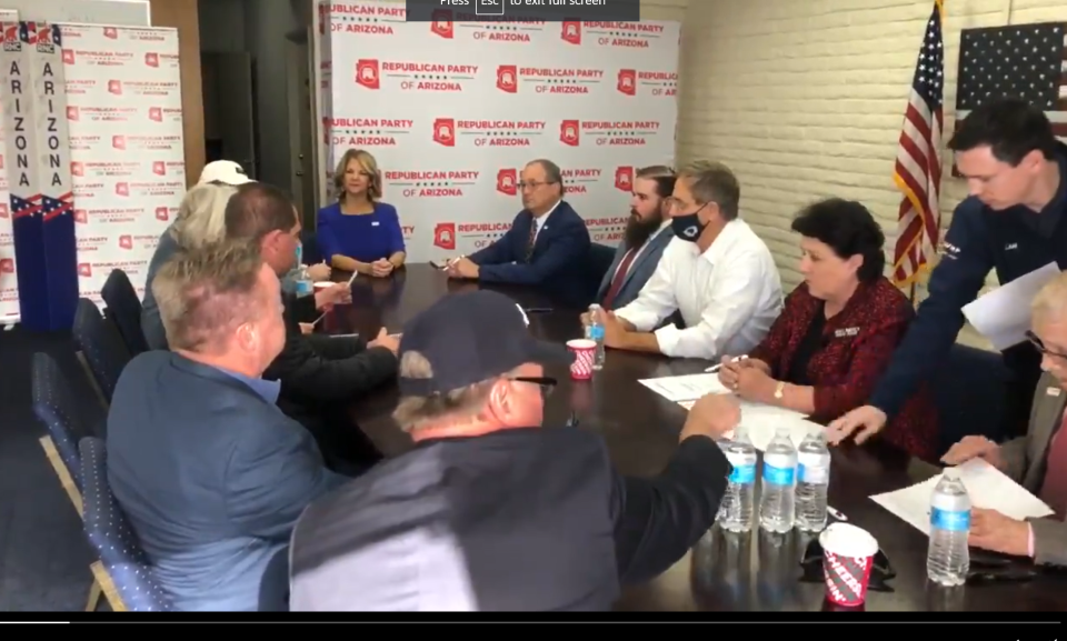 A screenshot of a video posted on Twitter by the Arizona Republican Party shows a man (standing) wearing a dark Trump jacket with the name Lane on it at the December 2020 meeting where Republicans falsely declared themselves the state's presidential electors.