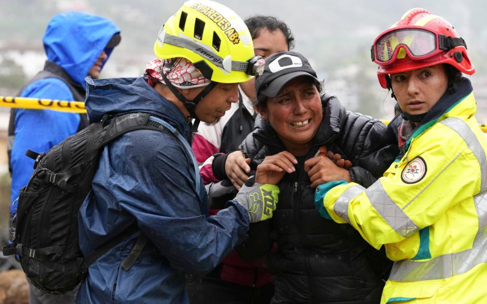 Rescue workers comfort a woman whose daughter is missing in Alausi, Ecuador, on Tuesday after a landslide buried dozens of homes - Dolores Ochoa/AP