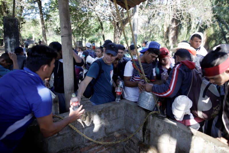 Migrants, mainly from Central America and marching in a caravan, draw water from a well during a break near Frontera Hidalgo, Chiapas