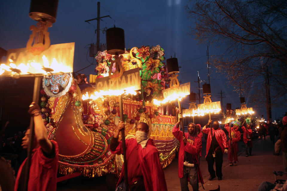 Fleambeaux Carriers march along side the Captain's float in the Mardi Gras parade in New Orleans, Monday, Feb. 20, 2012.(AP Photo/Bill Haber)