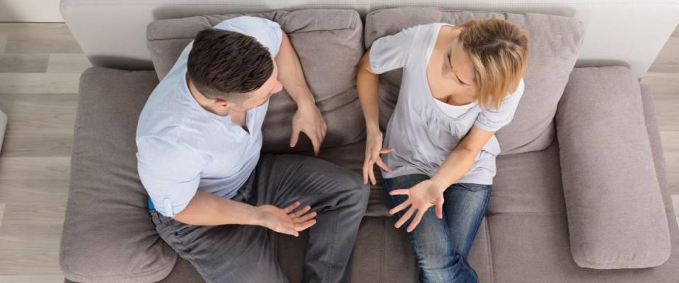 Overhead View Of A Couple Sitting On Couch Having Discussion At Home