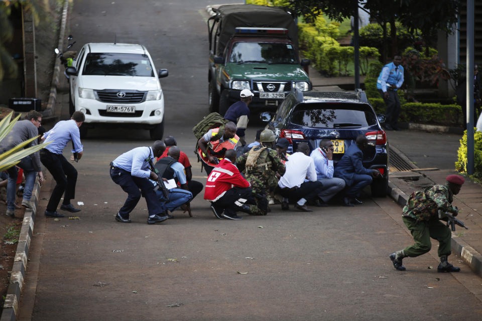 People take cover after an attack on a hotel, in Nairobi, Kenya, Tuesday, Jan. 15, 2019. Extremists launched a deadly attack on a luxury hotel in Kenya's capital Tuesday, sending people fleeing in panic as explosions and heavy gunfire reverberated through the complex. A police officer said he saw bodies, "but there was no time to count the dead." (AP Photo/Brian Inganga)