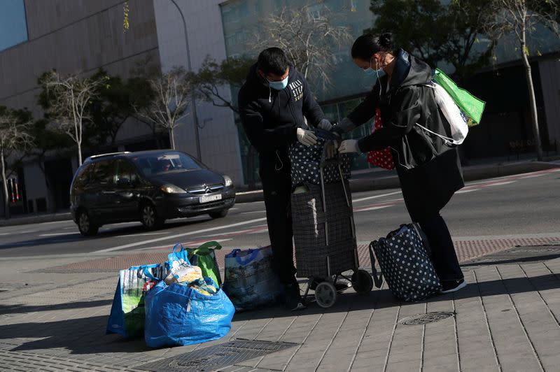 Personas utilizan mascarillas mientras reorganizan sus compras para tres hogares durante el brote dede coronavirus (COVID-19) en Madrid