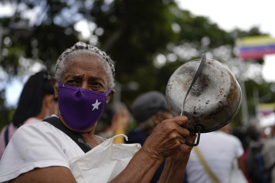 Una manifestante golpea una olla para referirse al hambre durante una manifestación de trabajadores públicos activos y jubilados, incluidos maestros, que exigen mejores salarios y el resto de su bono de vacaciones que dicen fue pagado parcialmente, mientras marchan hacia el Ministerio de Trabajo en Caracas, Venezuela, el martes 2 de agosto de 2022. (Foto AP/Ariana Cubillos)