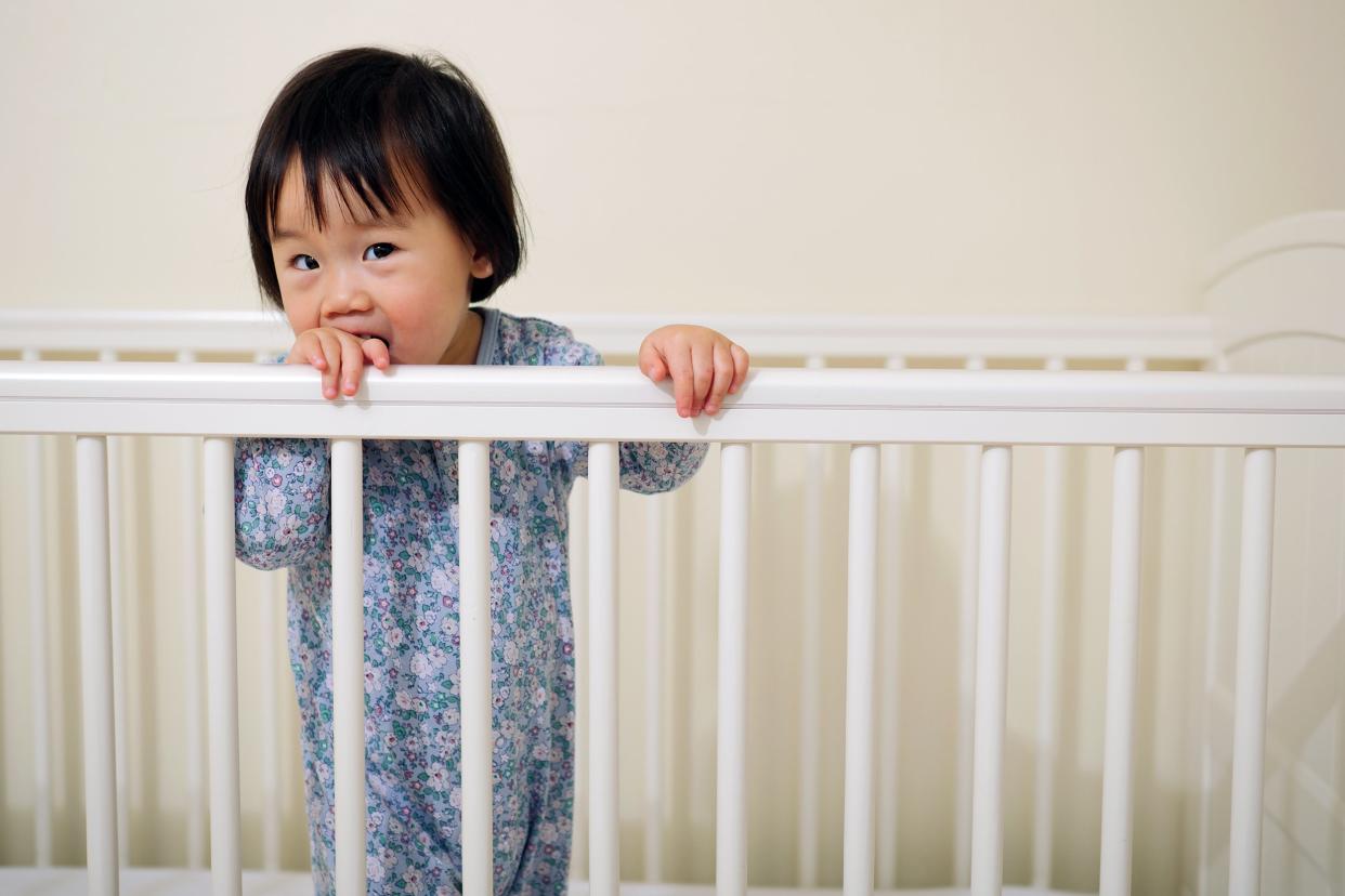 Little girl standing in her crib