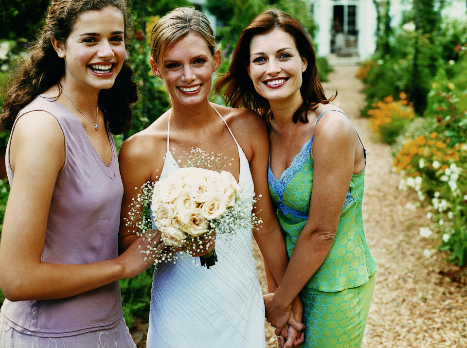 Bride stands with two wedding guests on her wedding day