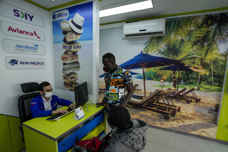 An agent at NewStilo travel agency assists customers in Santiago, Chile, Friday, March 25, 2022. John Paul Spode, who manages NewStilo, said few places have the demand for charter flights like Haiti, though he said it’s not an easy place for a business to operate. (AP Photo/Esteban Felix)