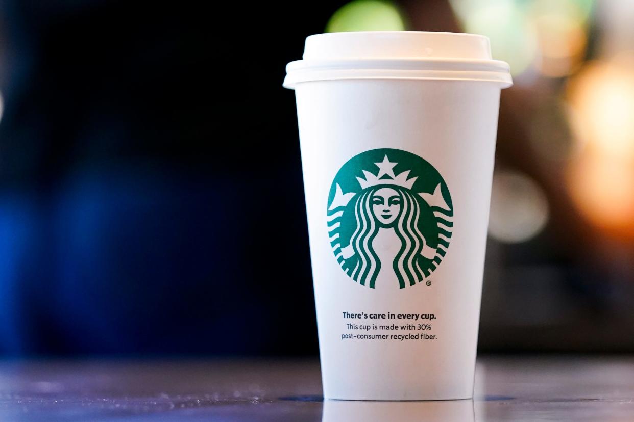 A single-use cup made from 30% post-consumer recycled fiber sits at a Starbucks retail location in Seattle. The company's goal is to cut waste, water use and carbon emissions in half by 2030.