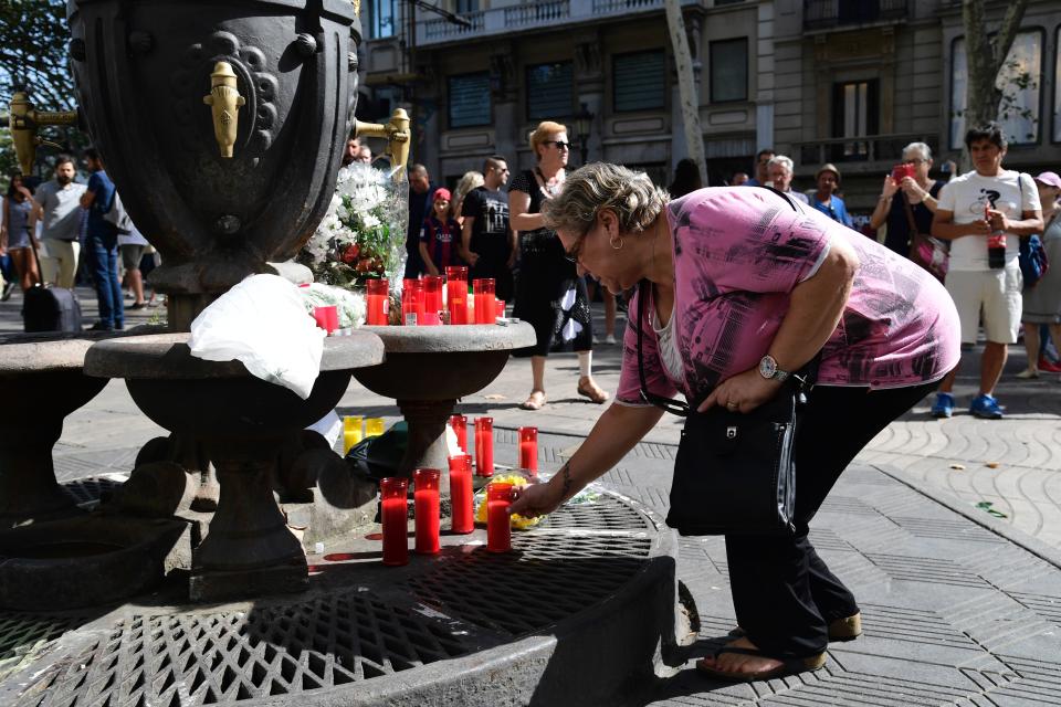 A woman lights a candle at the Canaletas fountain.