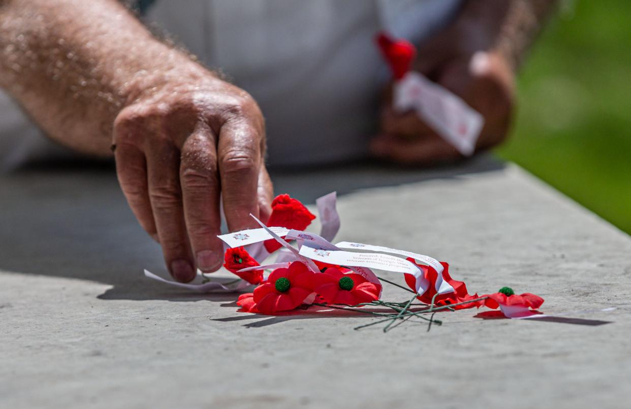 Keith Reimer, Commander of American Legion Post 399 in Okauchee, places a poppies on the tomb of the unknown solder at La Belle Cemetery in Oconomowoc during the Memorial Day Remembrance ceremony on Monday, May 25, 2020. Each poppy represents a local veteran who passed away this year.