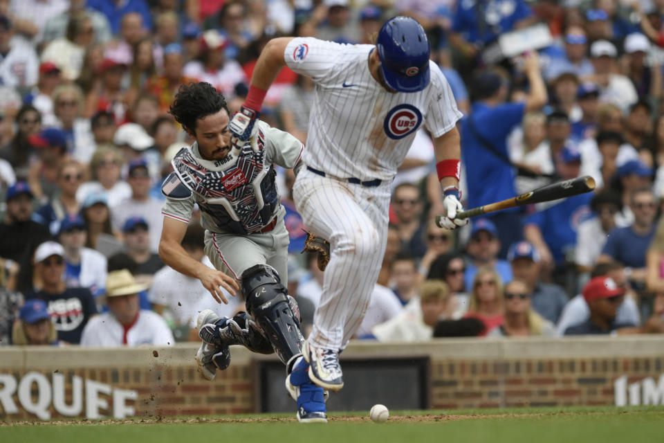 Chicago Cubs' Patrick Wisdom, right, runs to first as Philadelphia Phillies catcher Garrett Stubbs, left, runs down a ground ball before throwing him out at first during the fourth inning of a baseball game Thursday, July 4, 2024, in Chicago. (AP Photo/Paul Beaty)