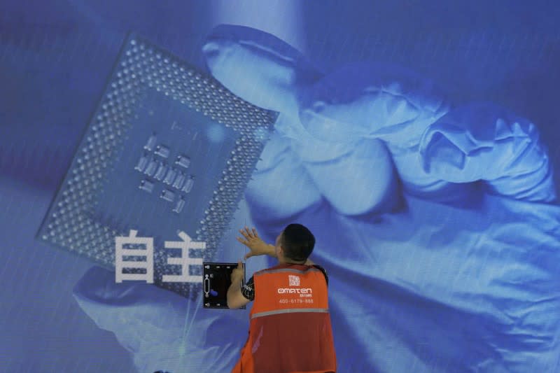 <cite>2023年7月5日，在上海舉行的世界AI大會期間，一名工人正在檢查顯示電腦晶片與中文「自主」字樣的螢幕。（美聯社）</cite>