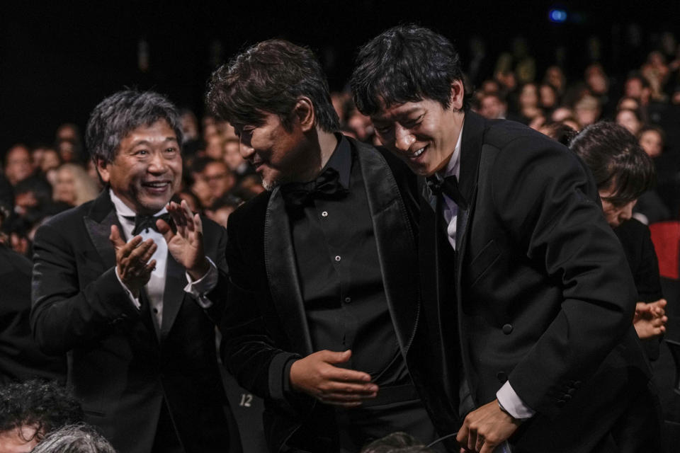 Song Kang-ho, centro, va por su premio a mejor actor por “Broker” mientras es felicitado por el director Hirokazu Koreeda, izquierda, y Dong-won Gang durante la ceremonia de premiación de la 75a edición del Festival de Cine de Cannes, en Francia el 28 de myo de 2022. (Foto Joel C Ryan/Invision/AP)