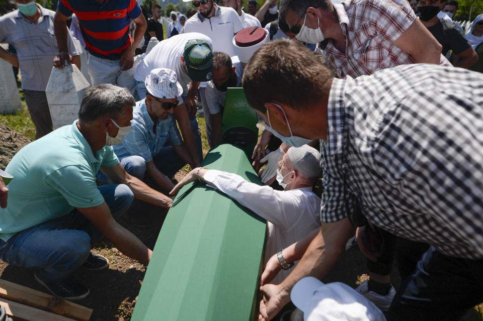 A massacre victim's remains are buried in Potocari, near Srebrenica, Bosnia, Saturday, July 11, 2020. Mourners converged on the eastern Bosnian town of Srebrenica for the 25th anniversary of the country's worst carnage during the 1992-95 war and the only crime in Europe since World War II that has been declared a genocide. (AP Photo/Kemal Softic)