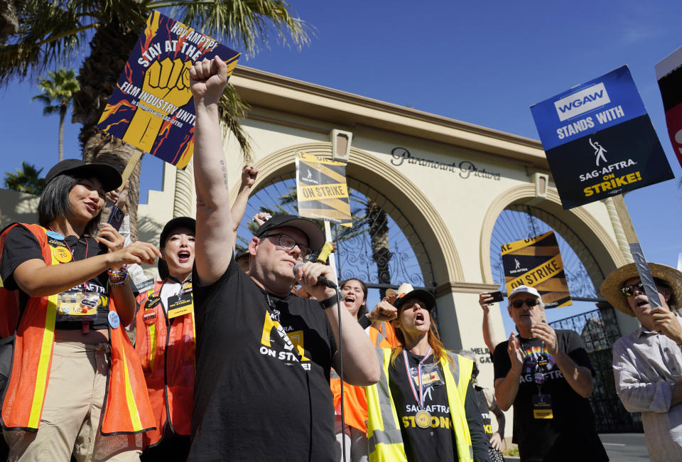 FILE - SAG-AFTRA chief negotiator Duncan Crabtree-Ireland, left, raises a fist as he rallies striking actors outside Paramount Pictures studio, Friday, Nov. 3, 2023, in Los Angeles. According to an annual report published Thursday, Feb. 15, 2024, from the Labor Action Tracker, a collaboration between researchers at Cornell University and the University of Illinois, those involved in work stoppages climbed 141% in 2023 — from 224,000 to 539,000 striking workers. (AP Photo/Chris Pizzello)