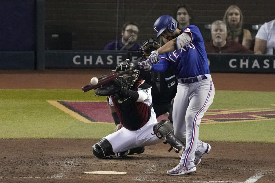 Texas Rangers' Marcus Semien, right, hits a two-run home run as Arizona Diamondbacks catcher Gabriel Moreno reaches for the pitch during the ninth inning in Game 5 of the baseball World Series Wednesday, Nov. 1, 2023, in Phoenix. (AP Photo/Ross D. Franklin)