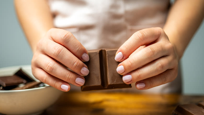 person breaking chocolate with fingers