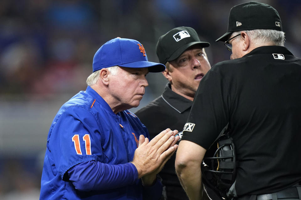 New York Mets manager Buck Showalter, left, talks with umpires during a replay review in the sixth inning of the team's baseball game against the Miami Marlins, Friday, June 24, 2022, in Miami. After review, Mets' Starling Marte was called safe at first. (AP Photo/Lynne Sladky)