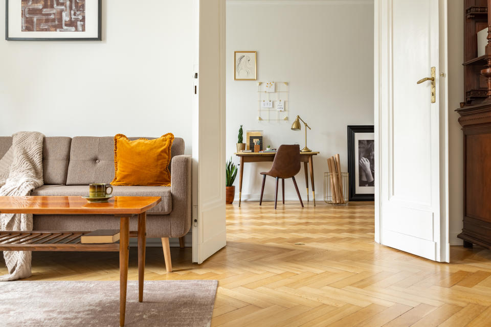 Real photo of a retro living room interior and view of a home office. View through a door