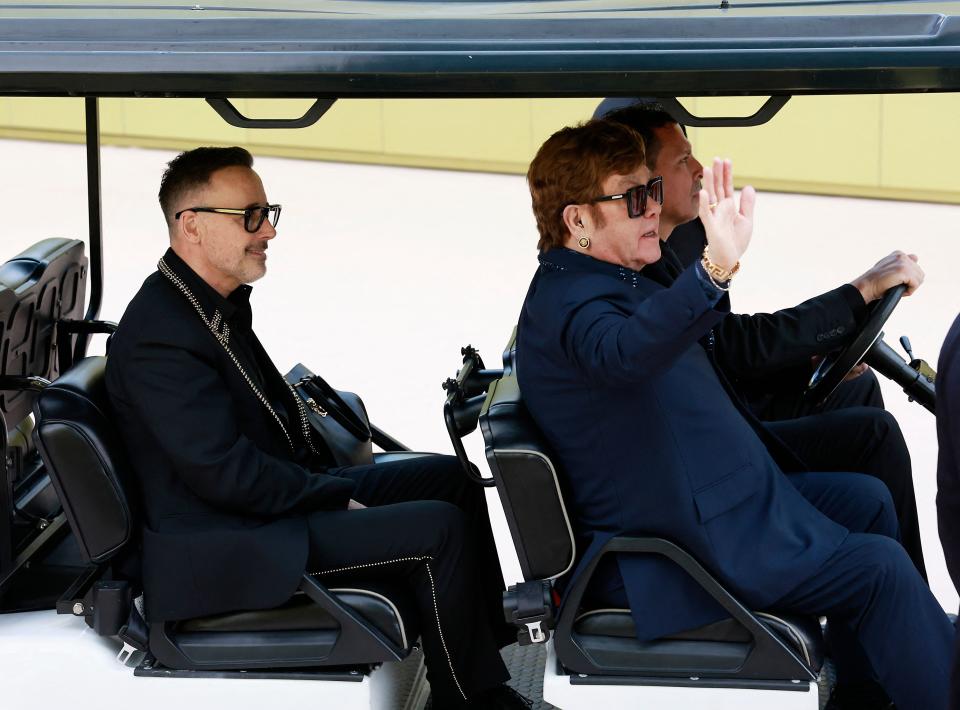 Elton John, right, and his husband David Furnish rolled up to the Versace Fall/Winter 2023 fashion show on Thursday in a golf cart.