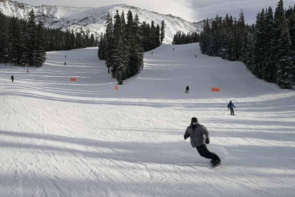 Skiers go down a hill at Arapahoe Basin Ski Area, on Thursday, Jan. 19, 2023, in Dillon, Colo. As global warming threatens to put much of the ski industry out of business over the next several decades, resorts are beginning to embrace a role as climate activists. (AP Photo/Brittany Peterson)