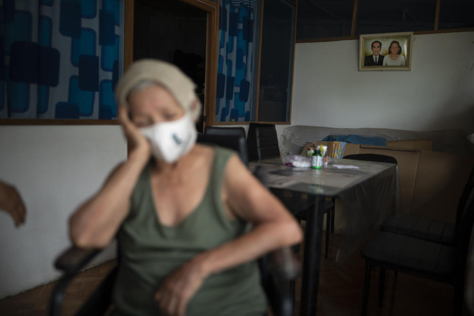 Suffering from a high fever related to dengue, 72-year-old Luz Rengifo rests inside her home, in Pucallpa, in Peru's Ucayali region, Tuesday, Sept. 29, 2020. A portrait of her mother Gertrudis Rengifo, who died last August from dengue at the age of 96, hangs in the background. (AP Photo/Rodrigo Abd)