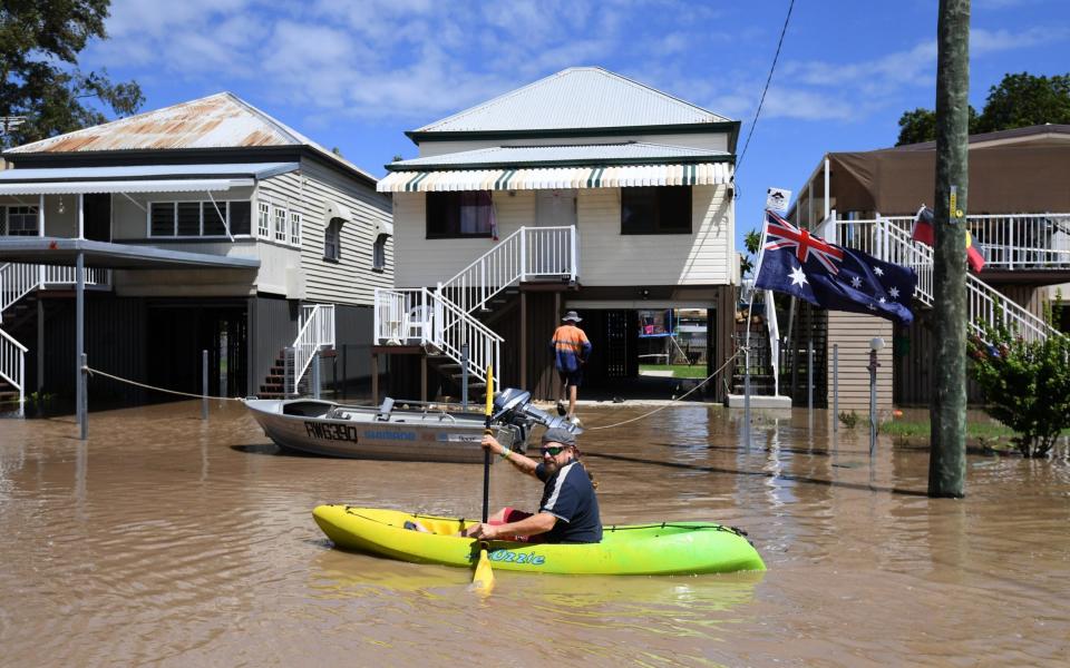 A local resident rows his kayak through floodwaters in the suburb of Depot Hill, in Australia's Queensland - Credit: AAP via EPA