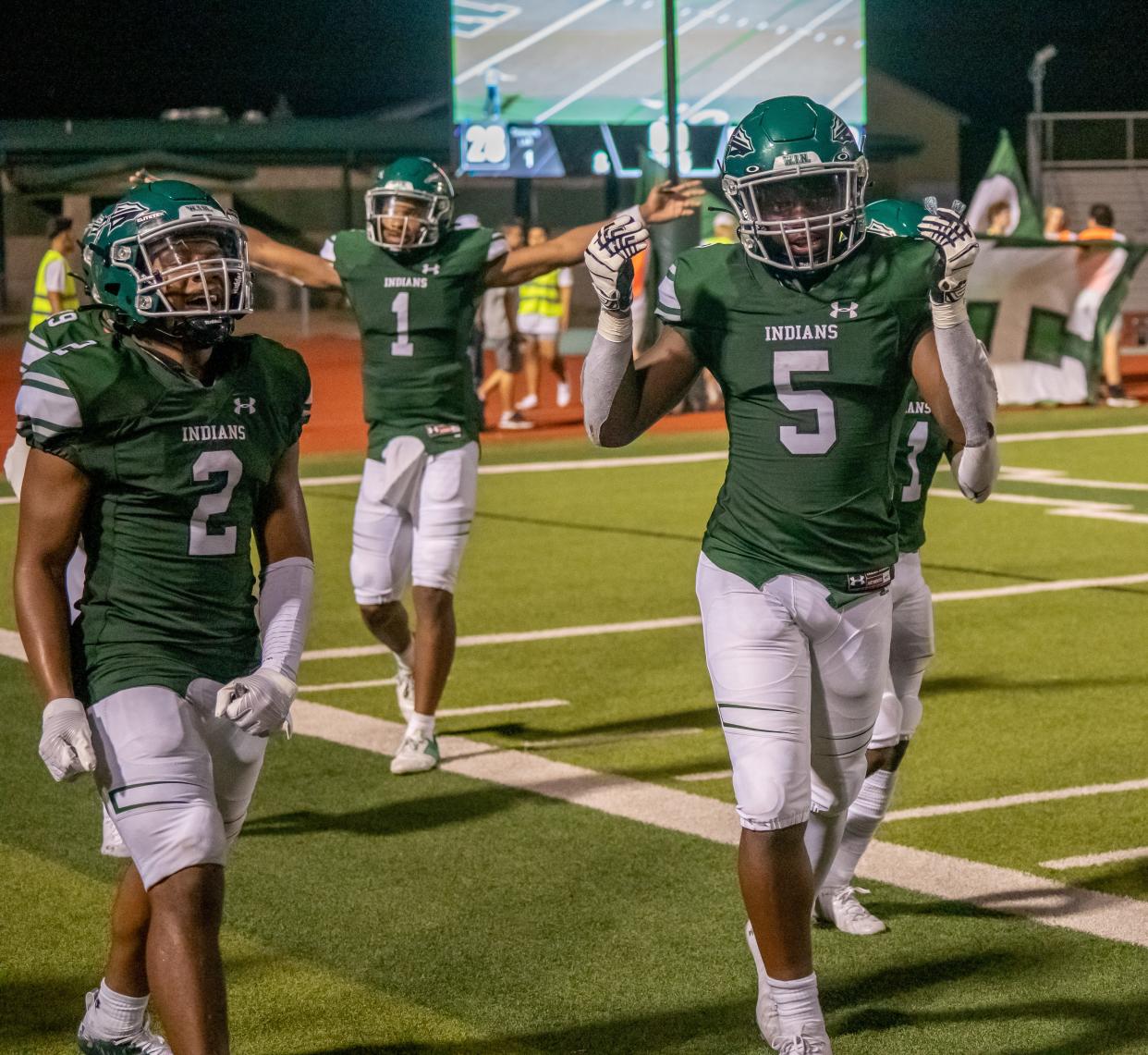 Waxahachie football players Iverson Young (2), Jayden Becks (5) and Roderick Hartsfield Jr. (1) celebrate as they walk off the field following the Indians' 28-22 overtime victory over Rowlett at Lumpkins Stadium in 2021.