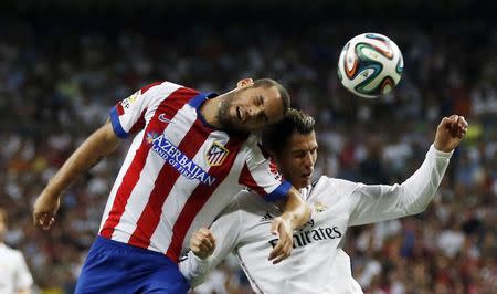 Real Madrid's Cristiano Ronaldo (R) and Atletico Madrid's Mario Suarez challenge for the ball during their Spanish Super Cup first leg soccer match at Santiago Bernabeu stadium in Madrid August 19, 2014. REUTERS/Sergio Perez