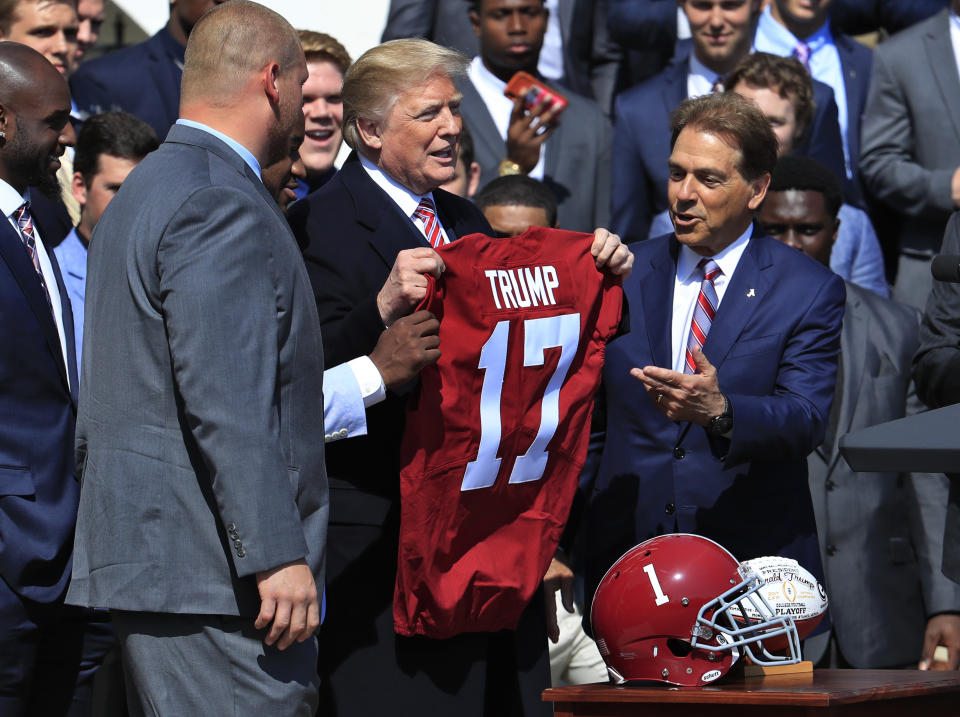 President Donald Trump holds up a team jersey presented to him by Alabama coach Nick Saban after their national championship win over Georgia in 2018.