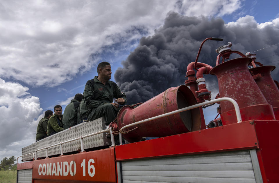 Firefighters move in a truck inside the Matanzas supertanker base to douse a fire that started during a thunderstorm, in Matanzas, Cuba, Sunday, Aug. 7, 2022. Cuban authorities say lightning struck a crude oil storage tank at the base, sparking a fire that sparked four explosions that injured more than 121 people, one person dead and 17 missing. (AP Photo/Ramon Espinosa)