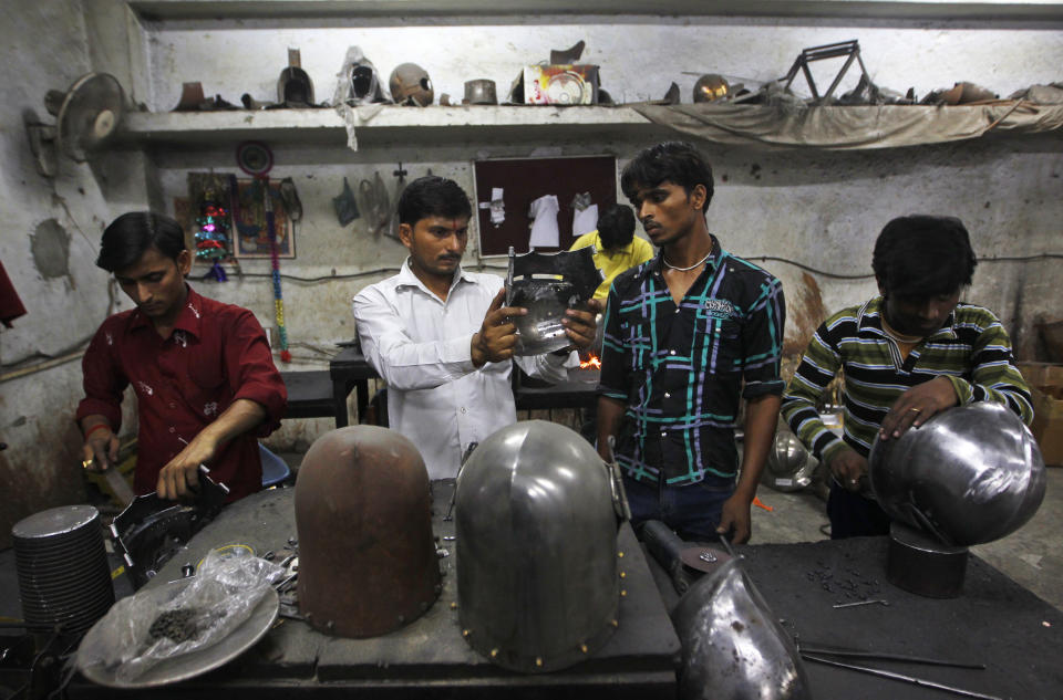 In this, June 2, 2012 photograph, a supervisor inspects helmets being prepared for a Hollywood period movie at a workshop owned by Indian businessman Ashok Rai, unseen, in Sahibabad, India. From Hollywood war movies to Japanese Samurai films to battle re-enactments across Europe, Ashok Rai is one of the world's go-to men for historic weapons and battle attire. (AP Photo/Saurabh Das)