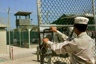 In this photo reviewed by US military officials, a guard opens a gate while in the background two detainees sit in a rest area behind fencing, within the grounds of Camp Delta 4 military-run prison, at the Guantanamo Bay U.S. Naval Base, Cuba June 27, 2006. The U.S. Supreme Court is preparing a potential landmark ruling that could determine the fate of the military tribunals created by President George W. Bush to try Guantanamo prisoners for war crimes. The ruling by the nation's highest court, which is expected later this week, will be one of the most significant presidential war powers cases since World War Two and could determine whether the tribunals are lawful. REUTERS/Brennan Linsley/Pool